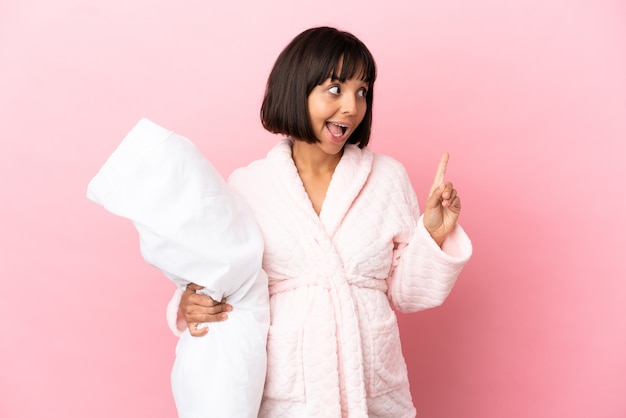 Young mixed race pregnant woman isolated on pink background in pajamas and intending to realizes the solution while lifting a finger up