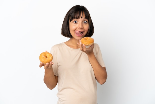 Young mixed race pregnant woman isolated on white background holding a donut