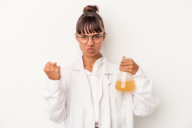 Young mixed race scientist woman holding a test tube isolated on white background  showing fist to camera, aggressive facial expression.