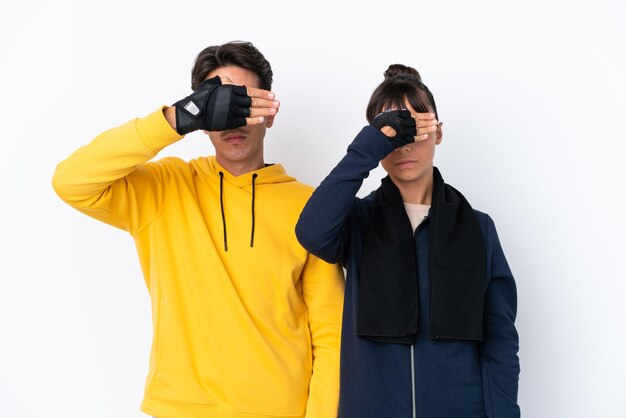 Young mixed race sport couple isolated on white background covering eyes by hands Do not want to see something