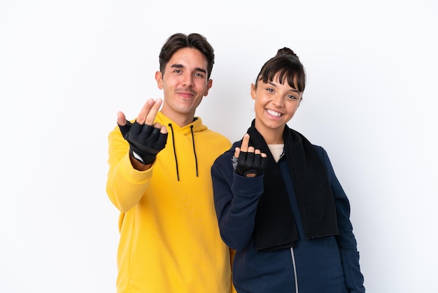 Young mixed race sport couple isolated on white background inviting to come with hand. Happy that you came