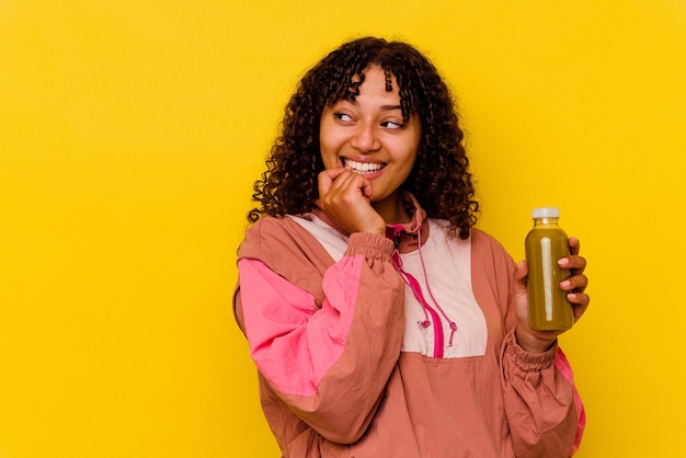Photo young mixed race sport woman holding a smoothie isolated on yellow background