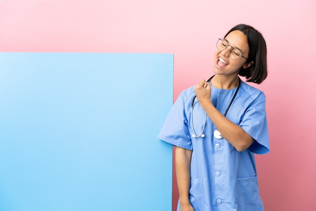 Photo young mixed race surgeon woman with a big banner over isolated background celebrating a victory