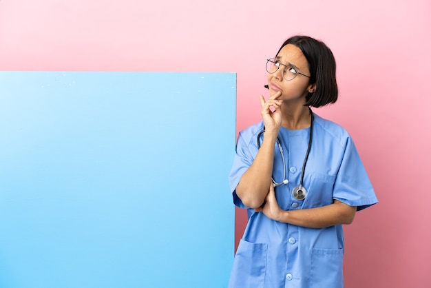 Young mixed race surgeon woman with a big banner over isolated background and looking up