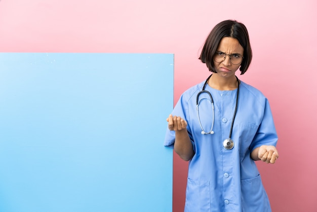 Young mixed race surgeon woman with a big banner over isolated background making money gesture but is ruined