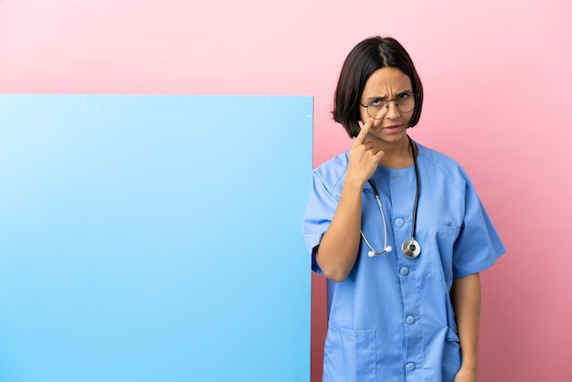 Young mixed race surgeon woman with a big banner over isolated background showing something