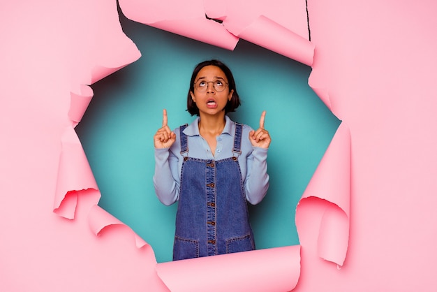 Young mixed race woman behind a broken background showing a horns gesture as a revolution concept.