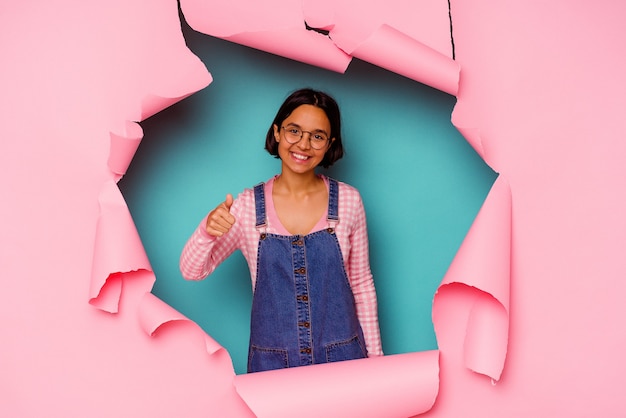 Young mixed race woman behind a broken background smiling confident with crossed arms.