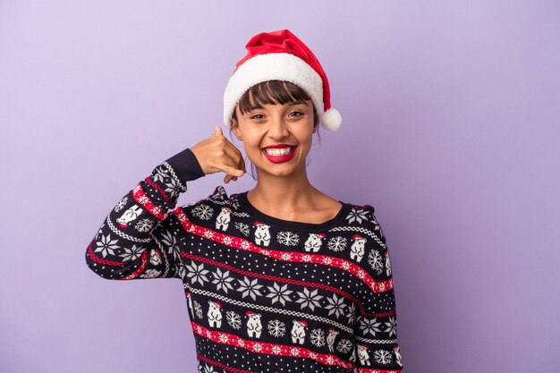 Young mixed race woman celebrating Christmas isolated on purple background  showing a mobile phone call gesture with fingers.