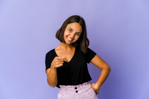 Young mixed race woman cheerful smiles pointing to front