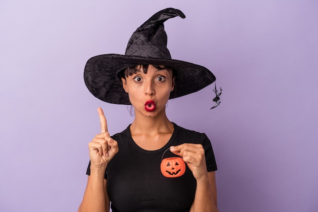 Young mixed race woman disguised as a witch isolated on purple background  having some great idea, concept of creativity.