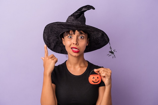 Photo young mixed race woman disguised as a witch isolated on purple background  showing a disappointment gesture with forefinger.