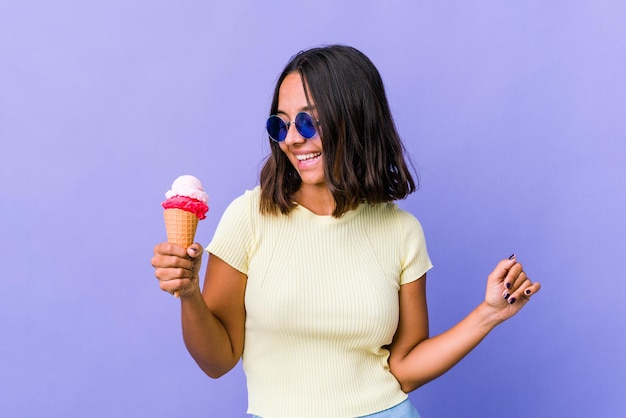 Giovane donna di razza mista che mangia un gelato ballando e divertendosi.