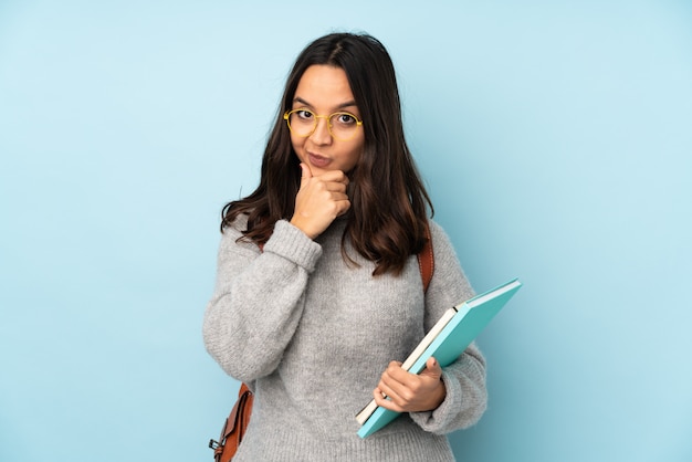 Photo young mixed race woman going to school isolated on blue wall thinking