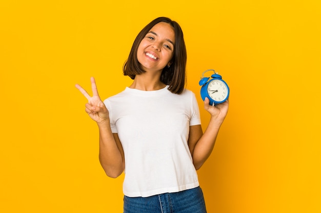 Young mixed race woman holding an alarm clock