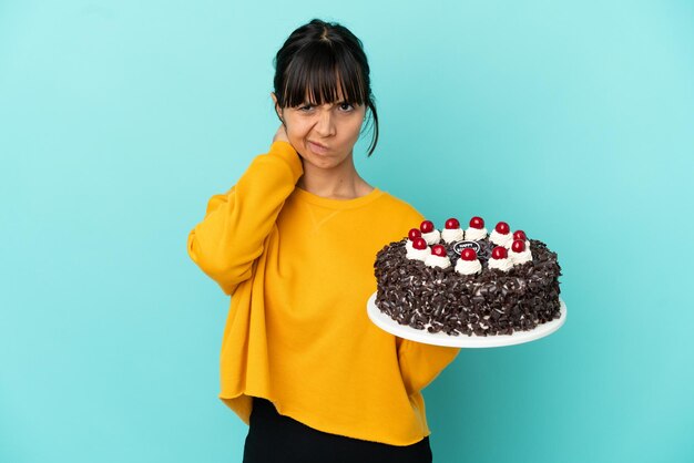 Young mixed race woman holding birthday cake having doubts