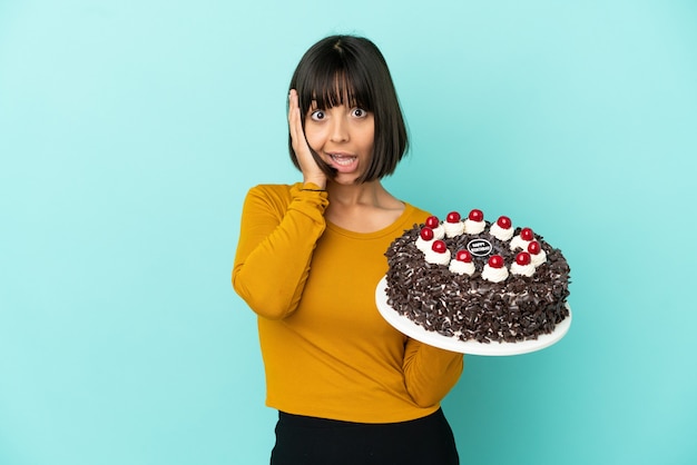 Young mixed race woman holding birthday cake with surprise expression