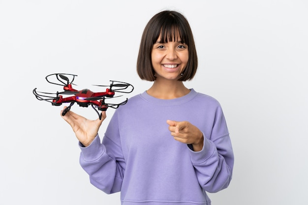 Young mixed race woman holding a drone isolated on white background pointing front with happy expression