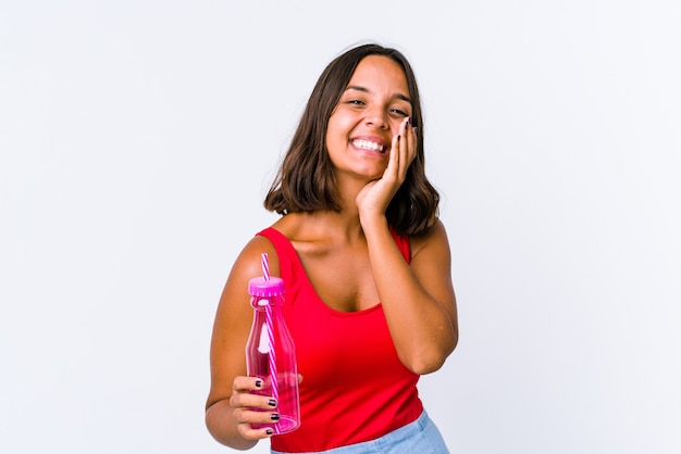 Young mixed race woman holding a milk shake isolated laughs happily and has fun keeping hands on stomach.