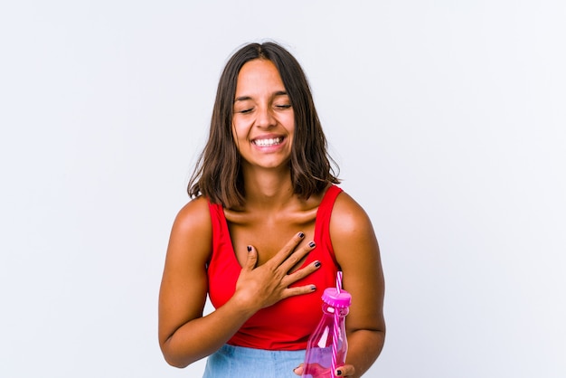 Young mixed race woman holding a milk shake isolated laughs out loudly keeping hand on chest.