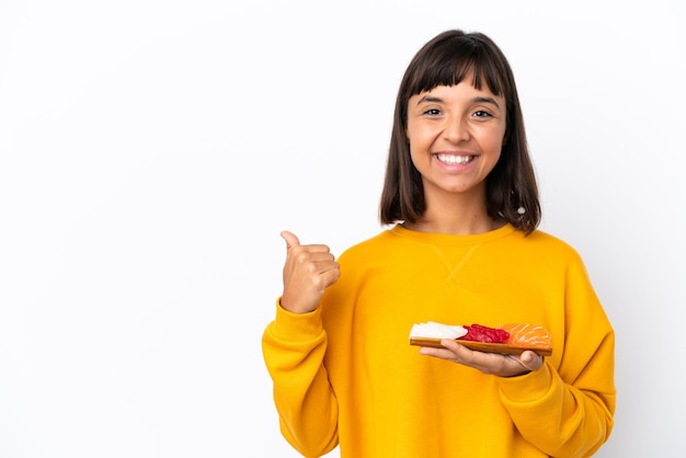 Young mixed race woman holding sashimi isolated on white background pointing to the side to present a product