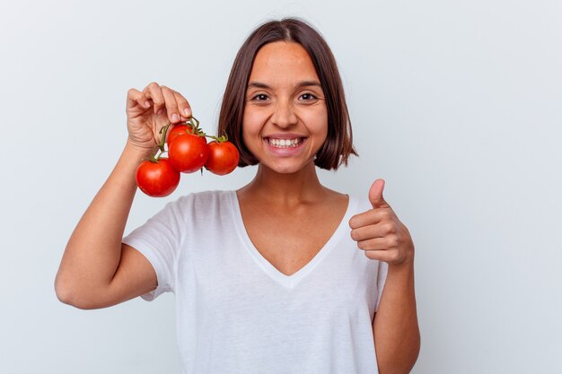 Photo young mixed race woman holding tomatoes isolated on white background