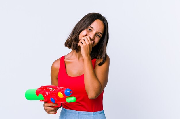 La giovane donna della corsa mista che tiene una pistola ad acqua ha isolato la risata felice, spensierata, emozione naturale.