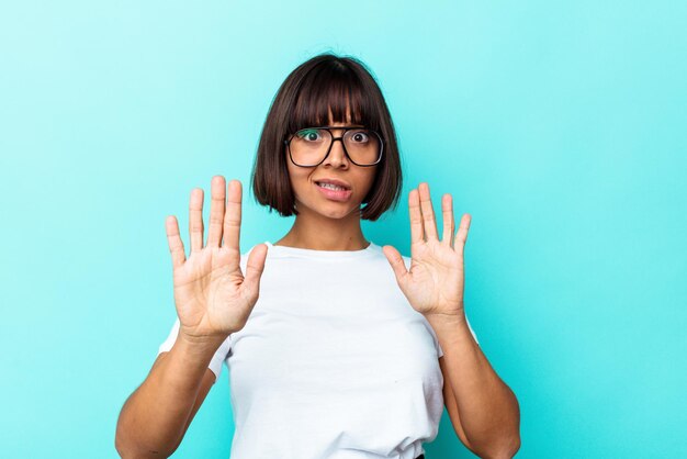 Young mixed race woman isolated on blue background being shocked due to an imminent danger