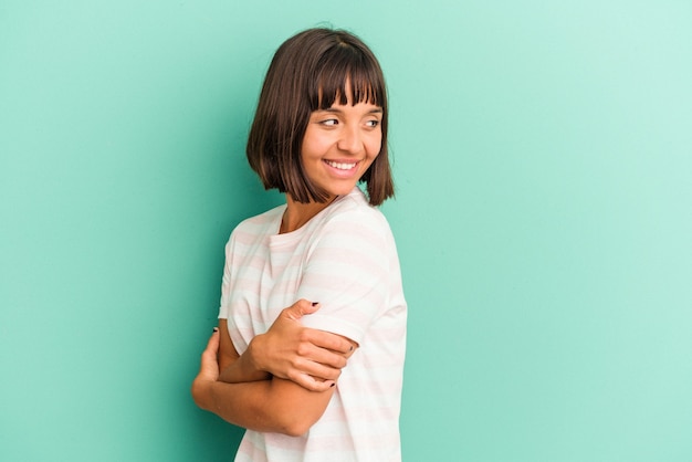 Young mixed race woman isolated on blue background blows cheeks, has tired expression. Facial expression concept.