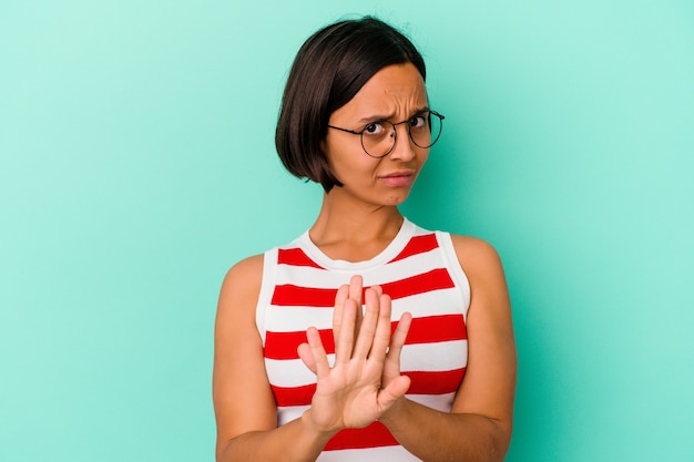 Young mixed race woman isolated on blue background doing a denial gesture