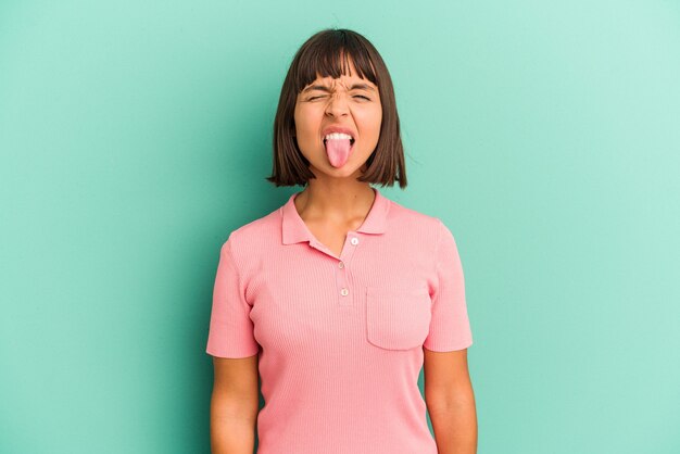 Young mixed race woman isolated on blue background funny and friendly sticking out tongue.