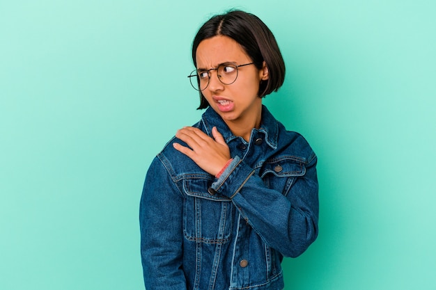 Young mixed race woman isolated on blue background having a shoulder pain.