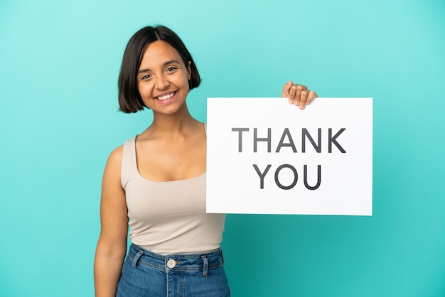 Young mixed race woman isolated on blue background holding a placard with text THANK YOU with happy expression