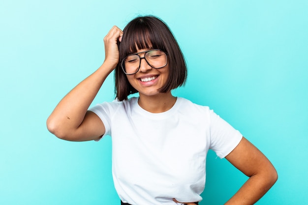 たくさん笑ってうれしそうな青い背景に孤立した若い混血の女性。幸福の概念。