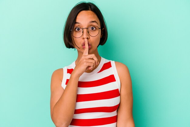 Young mixed race woman isolated on blue background keeping a secret or asking for silence.