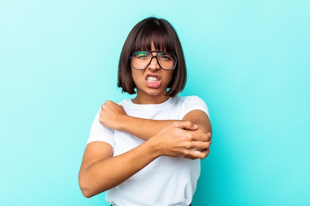 Photo young mixed race woman isolated on blue background massaging elbow, suffering after a bad movement.
