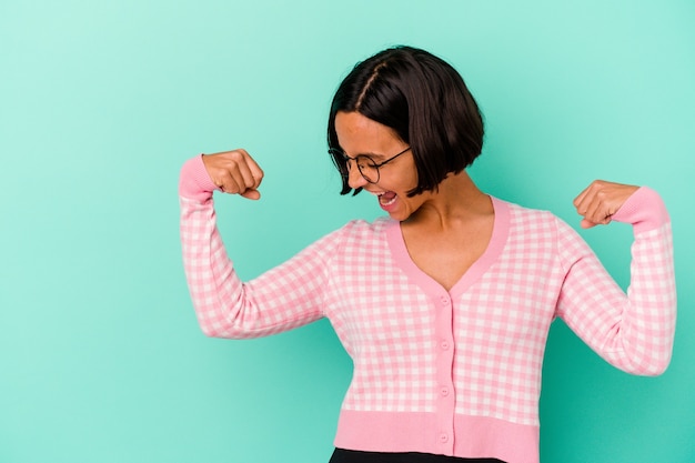 Young mixed race woman isolated on blue background raising fist after a victory, winner concept.