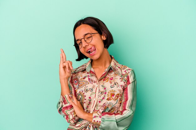 Young mixed race woman isolated on blue background showing rock gesture with fingers