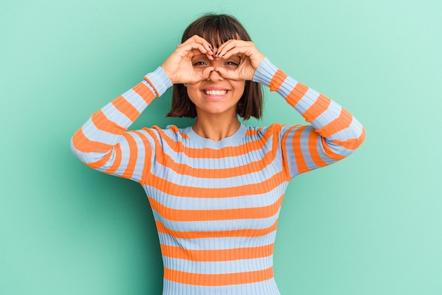 Young mixed race woman isolated on blue background showing rock gesture with fingers