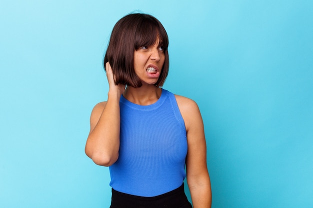 Young mixed race woman isolated on blue background tired and very sleepy keeping hand on head.