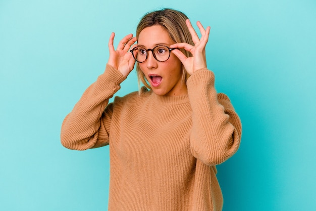 Young mixed race woman isolated on blue keeping eyes opened to find a success opportunity.