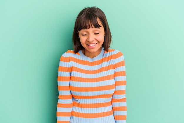 Photo young mixed race woman isolated on blue laughs and closes eyes, feels relaxed and happy.