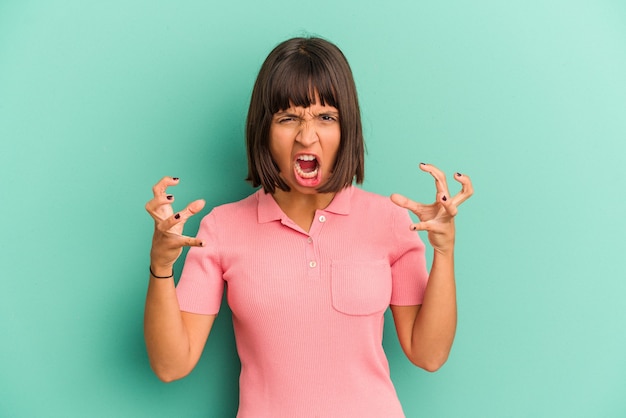 Young mixed race woman isolated on blue screaming with rage.