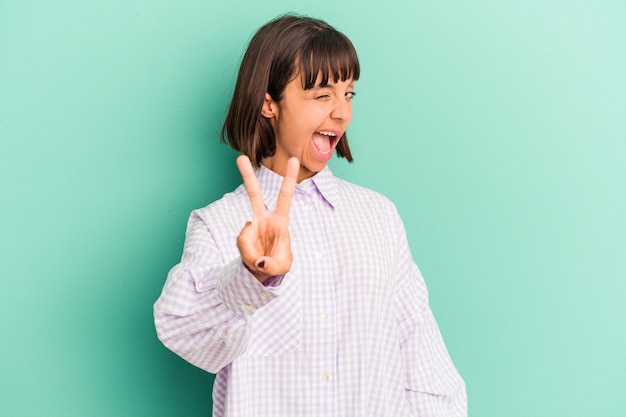 Young mixed race woman isolated on blue showing number two with fingers.