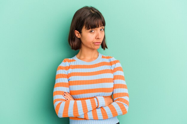 Young mixed race woman isolated on blue unhappy looking in camera with sarcastic expression.