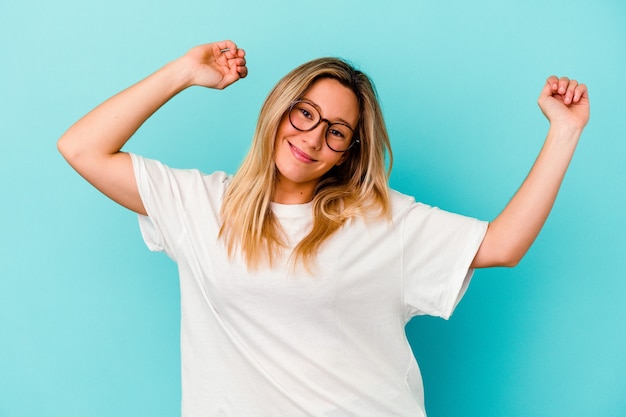 Young mixed race woman isolated on blue wall celebrating a special day, jumps and raise arms with energy.