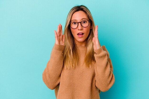 Young mixed race woman isolated on blue wall surprised and shocked.