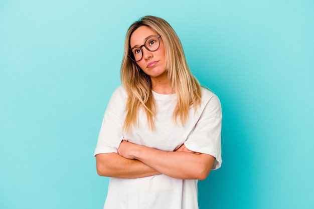 Young mixed race woman isolated on blue wall tired of a repetitive task.