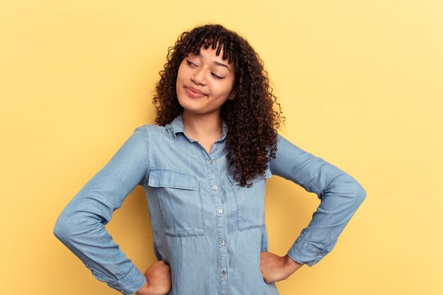 写真 目標と目的を達成することを夢見て黄色の背景に分離された若い混血の女性