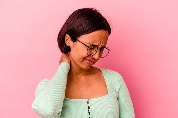 Young mixed race woman isolated on pink background having a neck pain due to stress, massaging and touching it with hand.